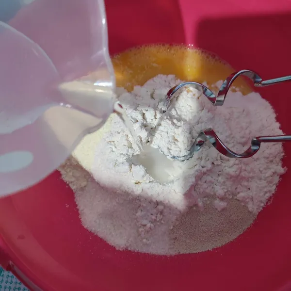 Masukkan terigu, gula, ragi instan dan ½butir telur kedalam wadah. Tuang air sedikit demi sedikit sampai membentuk adonan.