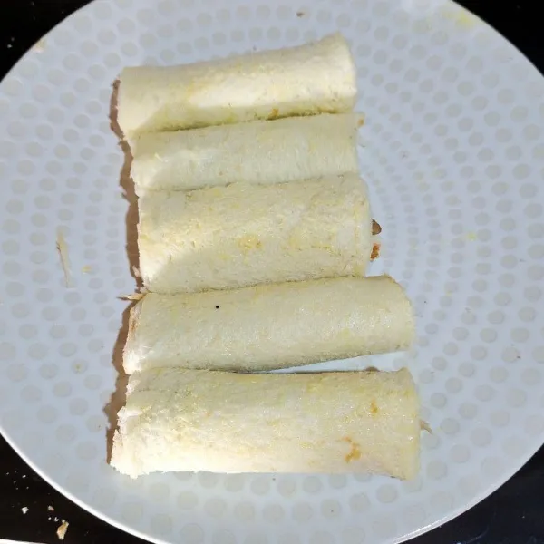 Gulung roti, kemudian oleskan mentega atau margarin. Panggang di wajan hingga kedua sisinya kering.