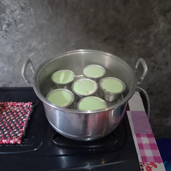 Pastikan panci pengukus dalam kondisi banyak uap panas. Kemudian masukkan cup ke dalam panci pengukus. Alasi tutup panci pengukus dengan serbet atau kain bersih.