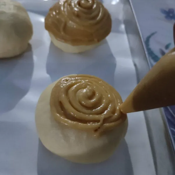 Diamkan kembali roti hingga mengembang 2x lipat. Kemudian semprotkan topping diatasnya secara melingkar. Sisakan 1½cm-2cm dari bagian dasar roti.