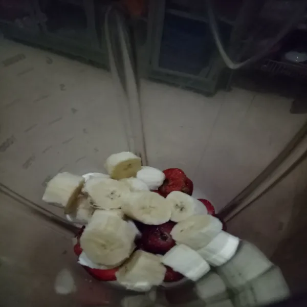 Potong-potong strawberry dan pisang, masukkan ke dalam blender.