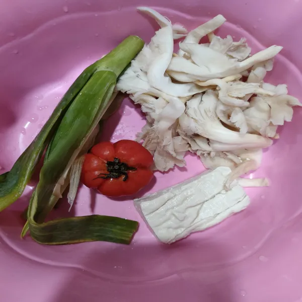 Siapkan semua bahan. Cuci jamur tiram sampi bersih, lalu peras sampai kandungan air hilang. Iris tipis bawang merah, lalu sisihkan dan potong daun bawang.
