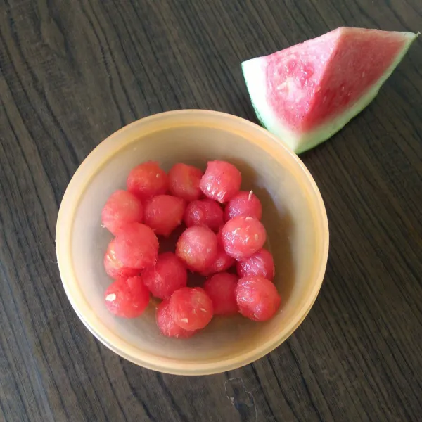 Cetak bulat buah semangka menggunakan sendok buah.