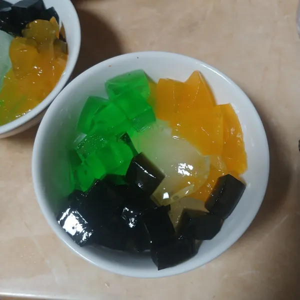 Dalam mangkok tuang es batu, beri jelly rasa cincau, jelly rasa melon dan puding mangga