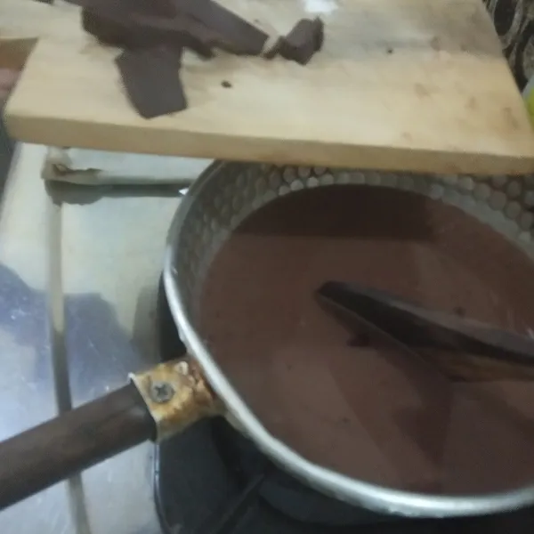 Setelah adonan hangat dan gula larut, masukkan coklat batang yang telah dipotong-potong kecil. Aduk dan terus masak hingga seluruh coklat batang larut dan matang.