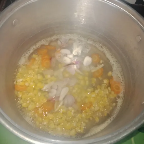 Lalu rebus jagung dan wortel, tambahkan rajangan bawang merah, bawang putih, rebus hingga matang.