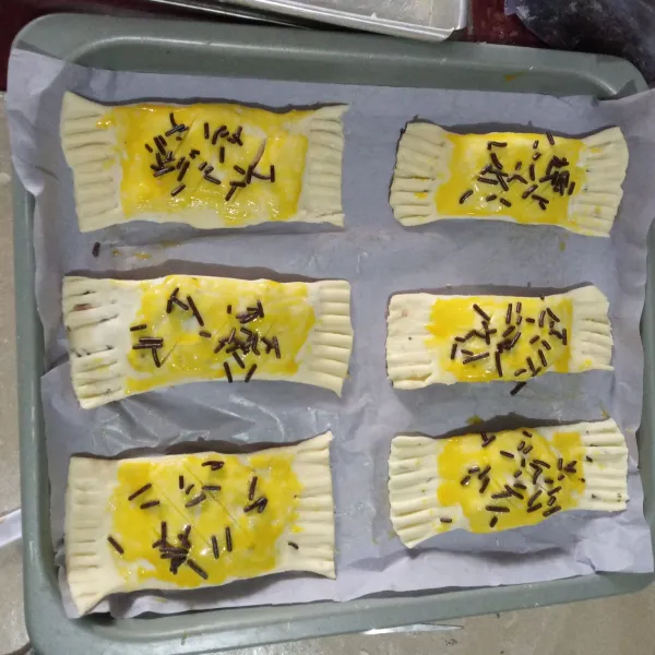 Olesi dengan kuning telur dan taburi dengan meises coklat. Masukkan dalam oven yang sudah dipanaskan sebelumnya.