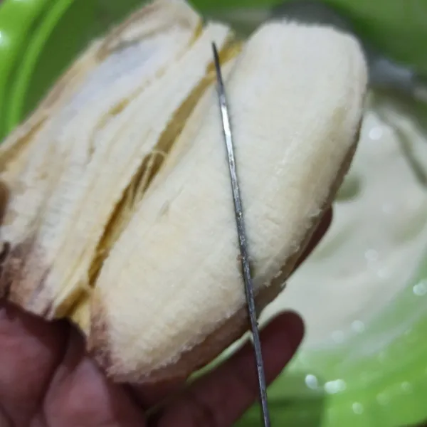 Kupas pisang lalu potong serong jadi 2 bagian.