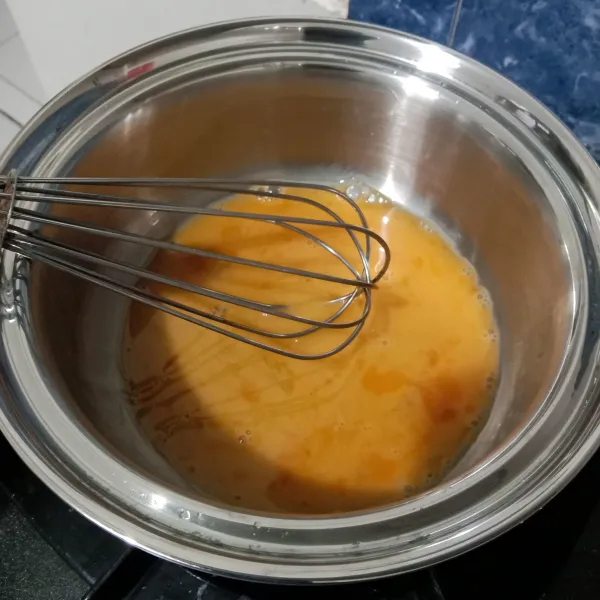 Dalam panci, kocok telur dengan whisk.