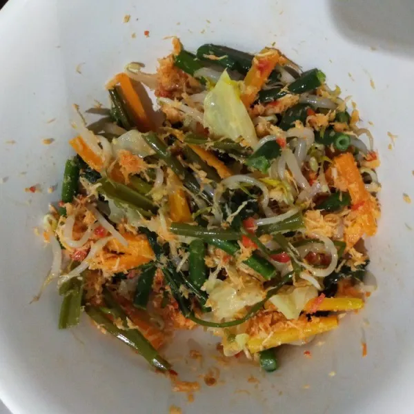 Tata sayuran di dalam mangkuk, beri bumbu urab, lalu aduk rata.