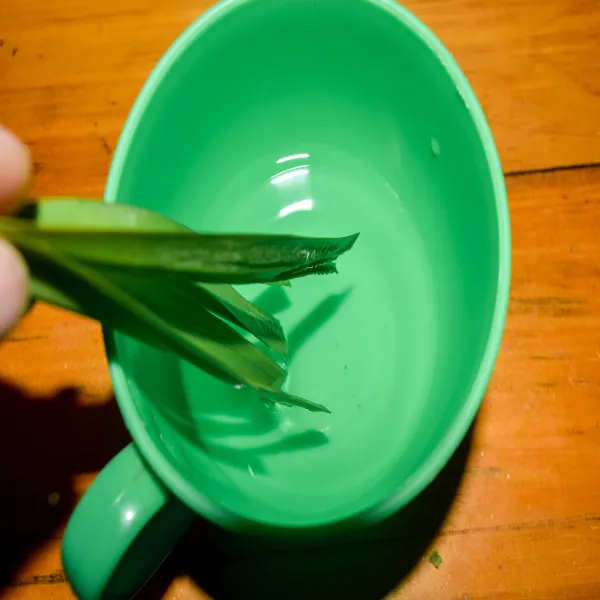 Siapkan bahan olesan untuk cetakan (air garam dan air). Gunting setengah bagian daun pandan sebagai kuas saat mengoles cetakan.