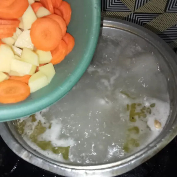 Menjelang matang, masukkan kentang dan wortel.