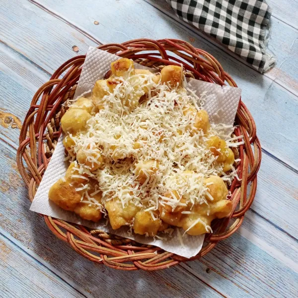 Tata pisang goreng di piring saji. Kucuri dengan kental manis, lalu taburi dengan keju parut. Sajikan.