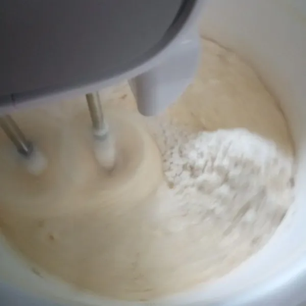 Kecilkan kecepatan mixer. Masukkan tepung terigu, baking powder dan susu bubuk yang telah diayak secara bertahap. Aduk balik.