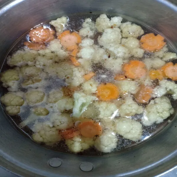 Tambahkan 1 liter air, lalu masukkan wortel dan kembang kol. Masak hingga mendidih.