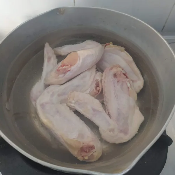 Cuci bersih sayap ayam, kemudian rebus hingga empuk. Buang air rebusan dan sisihkan.