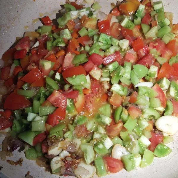 Setelah bawang merah dan bawang putih sudah harum, kemudian masukkan irisan tomat dan cabai, aduk sampai rata.