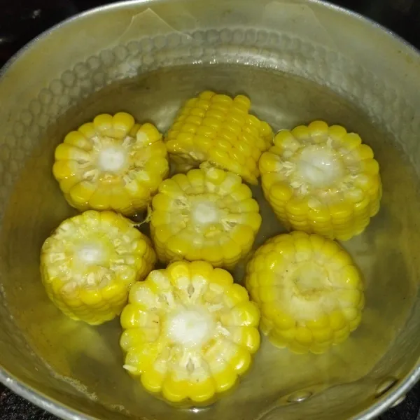 Siapkan 1 buah jagung manis, potong-potong, lalu rebus hingga matang.