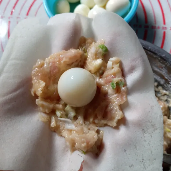Siapkan selembar kulit lumpia, beri sesendok adonan ayam, ratakan. Beri telur puyuh ditengah.