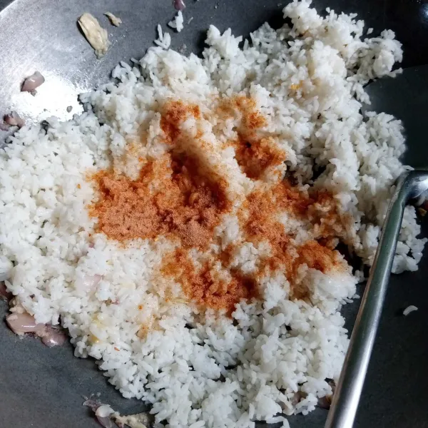 Masukkan nasi, taburi bumbu nasi goreng instan. Aduk-aduk hingga tercampur rata dengan bumbu.
