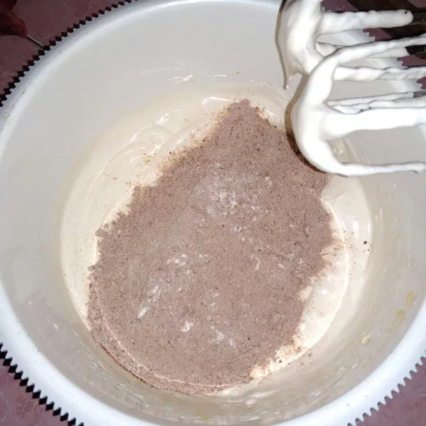 Tambahkan tepung terigu, coklat bubuk dan baking powder sambil diayak, mixer kecepatan rendah asal tercampur rata saja