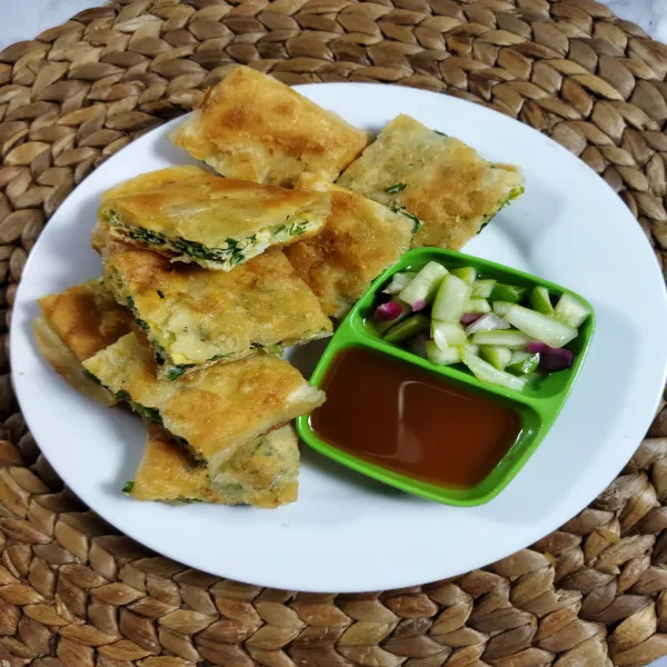 Sajikan martabak telur dengan kuah cuko dan acar mentimun.