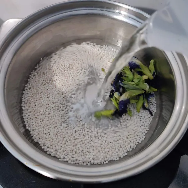 Masukkan sagu mutiara, bunga telang, dan 500 ml air ke dalam panci. Rebus hingga mendidih.