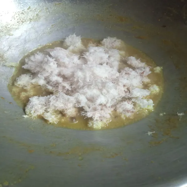 Nyalakan kompor, kemudian masukkan kelapa parut, aduk rata hingga kering.