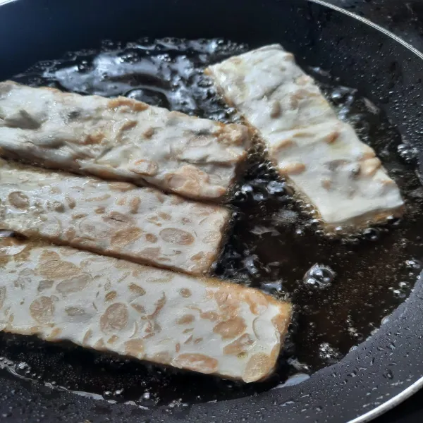 Goreng tempe yang sudah diberi garam.