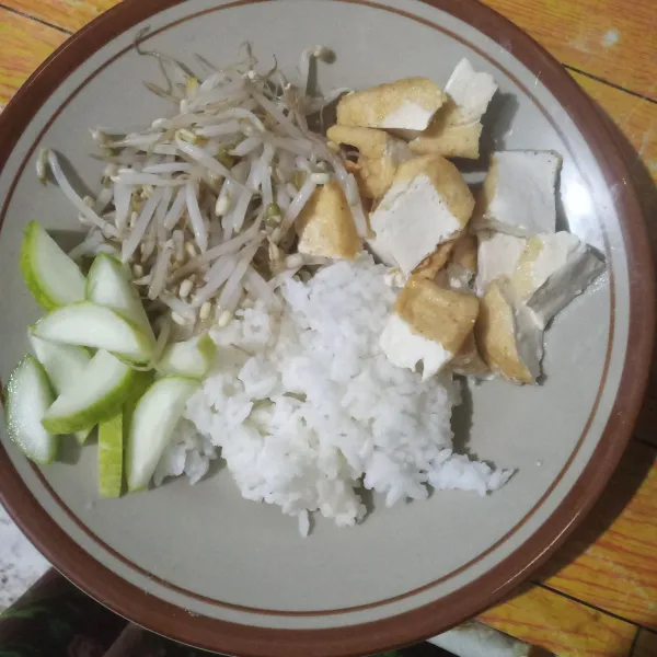 Ambil secukupnya nasi, beri tahu goreng yang sudah dipotong-potong, taoge dan acar mentimun.