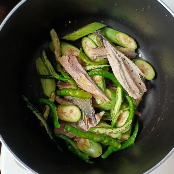 Dalam panci masukkan terong, ikan tongkol yang sudah di belah 2 dan cabe hijau.