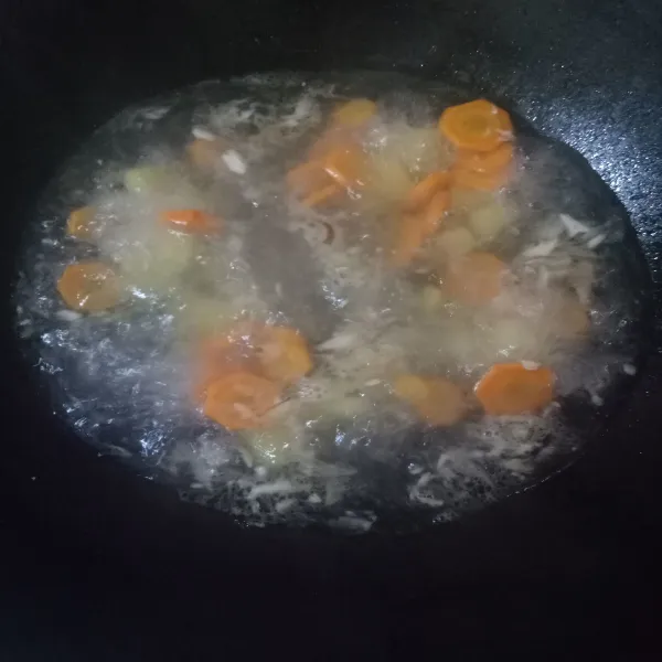 Lalu masukkan air, jika sudah mendidih, masukkan wortel dan kentang. Masak sampai setengah matang. Kemudian tambahkan garam, kaldu sapi, dan lada bubuk.