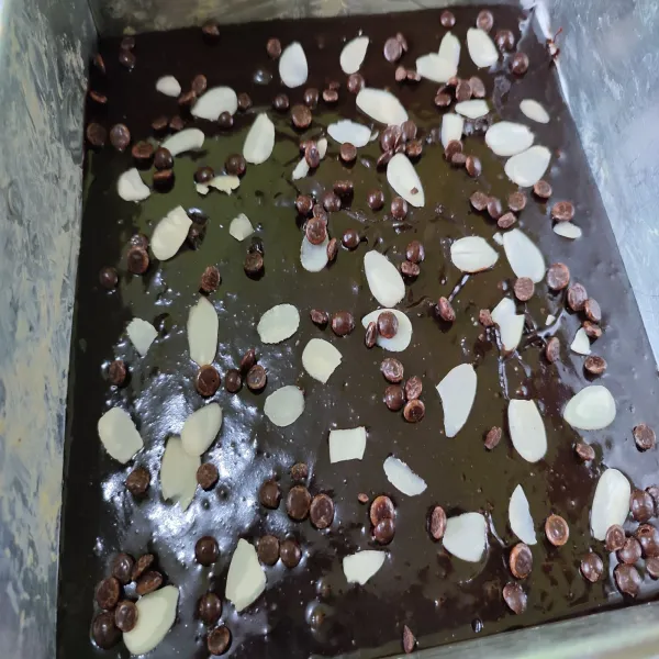 Taburkan kacang almond dan choco chips pada bagian atasnya.  Panggang di dalam oven dengan suhu 180°C hingga matang.