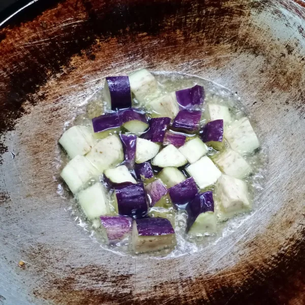 Potong kecil terong, cuci bersih. Kemudian goreng terong sampai layu.