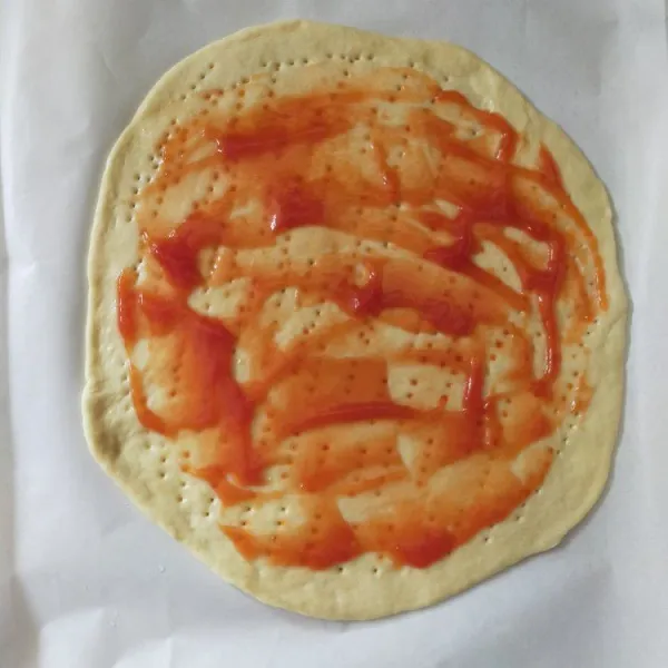 Giling adonan bentuk bulat. Lalu tusuk-tusuk dough dengan garpu. Olesi permukaan dough dengan minyak zaitun. Olesi dengan saus tomat.