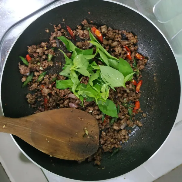 Jika rasa sudah sesuai selera, matikan api lalu tambahkan daun kemangi dan aduk rata. Sajikan bersama nasi atau mie, dipadukan dengan telur mata sapi.