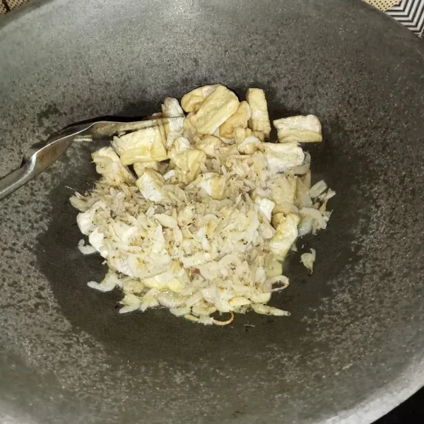 Masukkan tahu goreng dan udang rebon yang sudah dicuci bersih, lalu aduk rata.