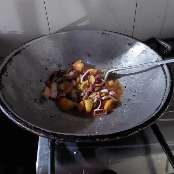 Selanjutnya masukkan cumi, tomat iris, kecap ikan, kaldu bubuk, garam dan gula pasir secukupnya, aduk-aduk.