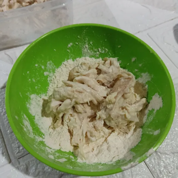 Ambil ayam sedikit demi sedikit, gulingkan di atas tepung kering.