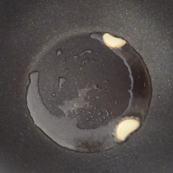 Panaskan minyak dengan api kecil, masukkan bawang putih yang sudah dipotong menjadi 2 bagian, dengan posisi bagian dalam menghadap ke bawah.