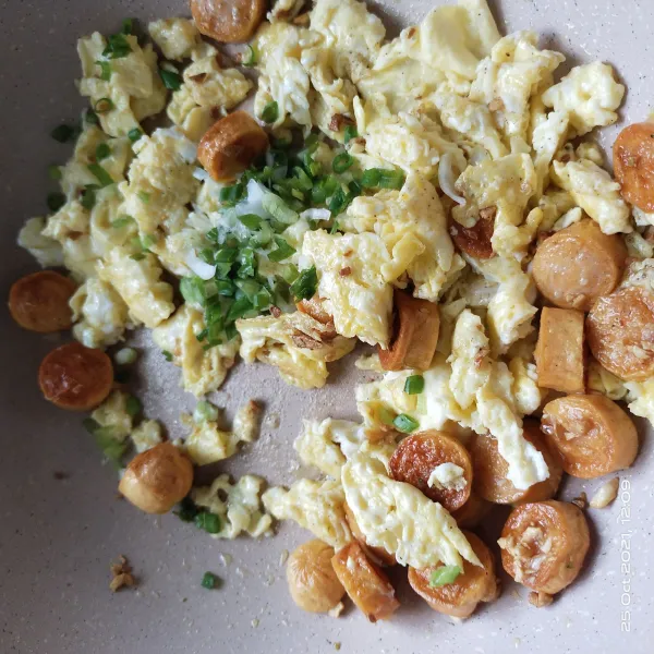 Masukkan daun bawang kedalam wajan orak arik telur, sosis dan aduk rata.
