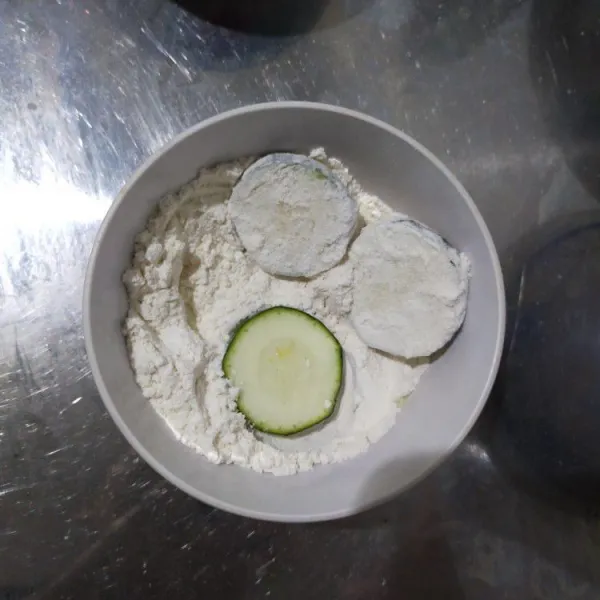 Balur tiap zucchini dengan tepung terigu.