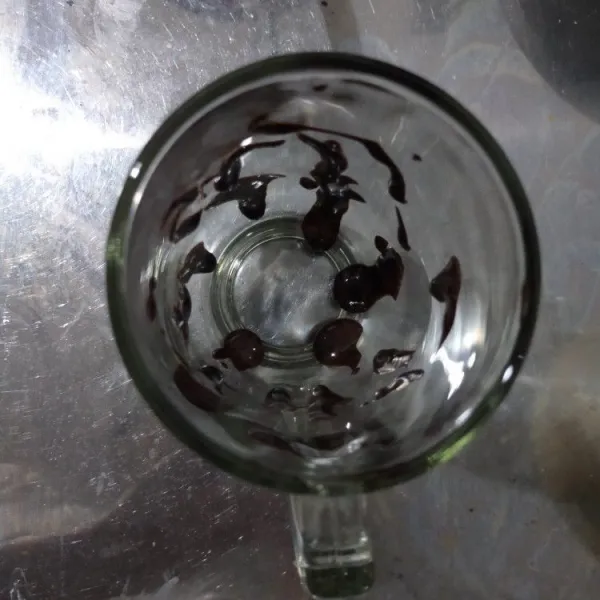 Ambil gelas saji, buat motif di pinggiran gelas dengan pasta cokelat.