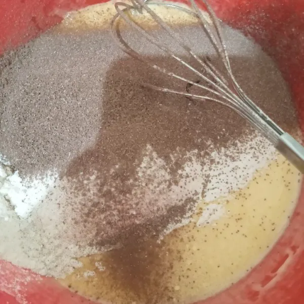 Tambahkan tepung terigu yang sudah diayak dan bubuk chocolatos. Aduk asal rata.