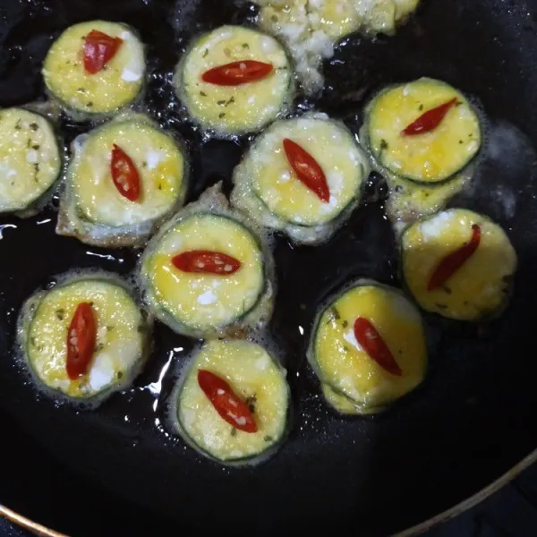 Goreng di wajan rata dengan secukupnya minyak hingga kedua sisi matang. Beri irisan cabai merah ketika bagian atas tepung masih basah agar cabai menempel di adonan.