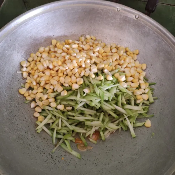 Setelah harum masukan jagung pipil dan labu beri sedikit air lalu tambahkan garam, merica bubuk, gula pasir, dan kaldu bubuk lalu aduk merata hingga matang.