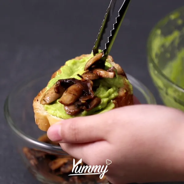 Oles baguette dengan alpukat, tambahkan tumis jamur dan sajikan.