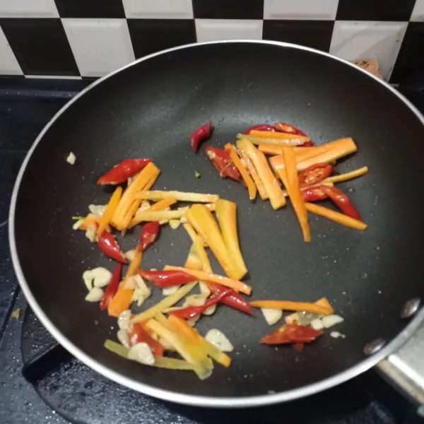 Tumis bawang putih dan cabai sampai harum, tambahkan potongan wortel, lalu aduk rata.