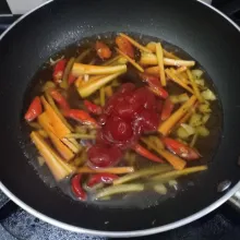 Setelah wortel agak layu, masukkan air, saus sambal, saus tomat, garam, gula dan lada bubuk, lalu aduk rata.