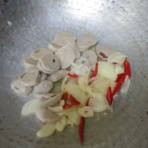 Tumis irisan cabai merah keriting, bawang putih, dan bawang bombay hingga harum. Masukkan irisan bakso, lalu aduk rata.